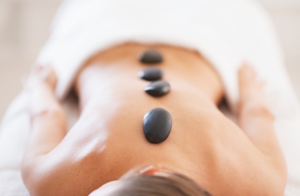 Body Treatments woman laying down with hot rocks on back